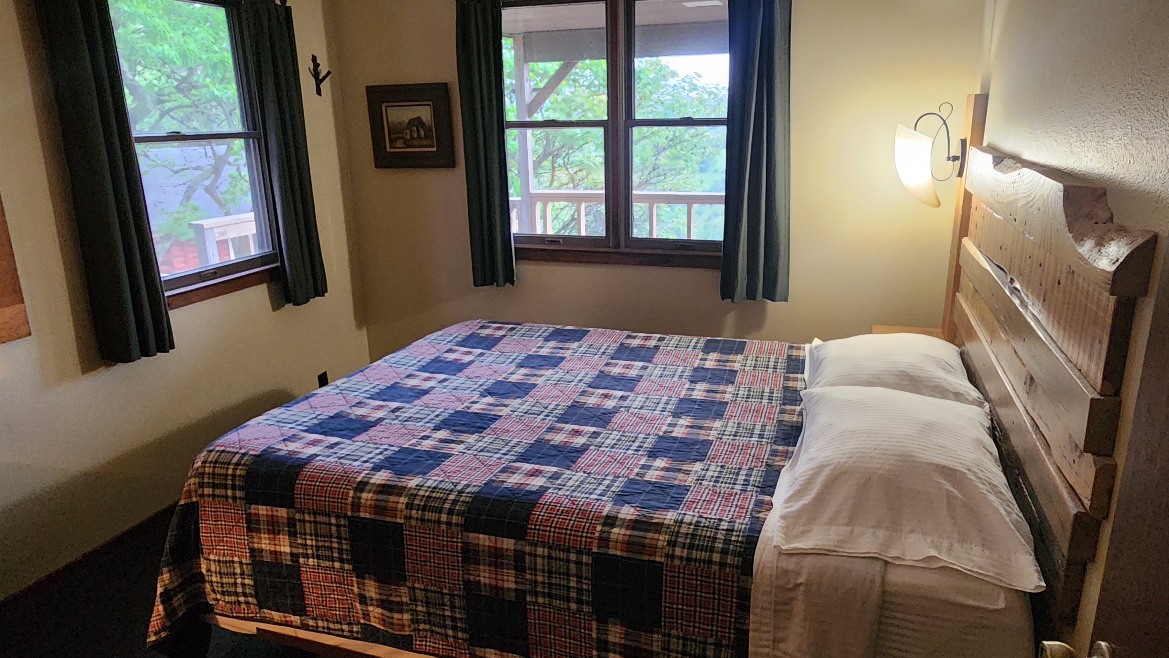 Valley View master bedroom wide view with two windows and framed artwork