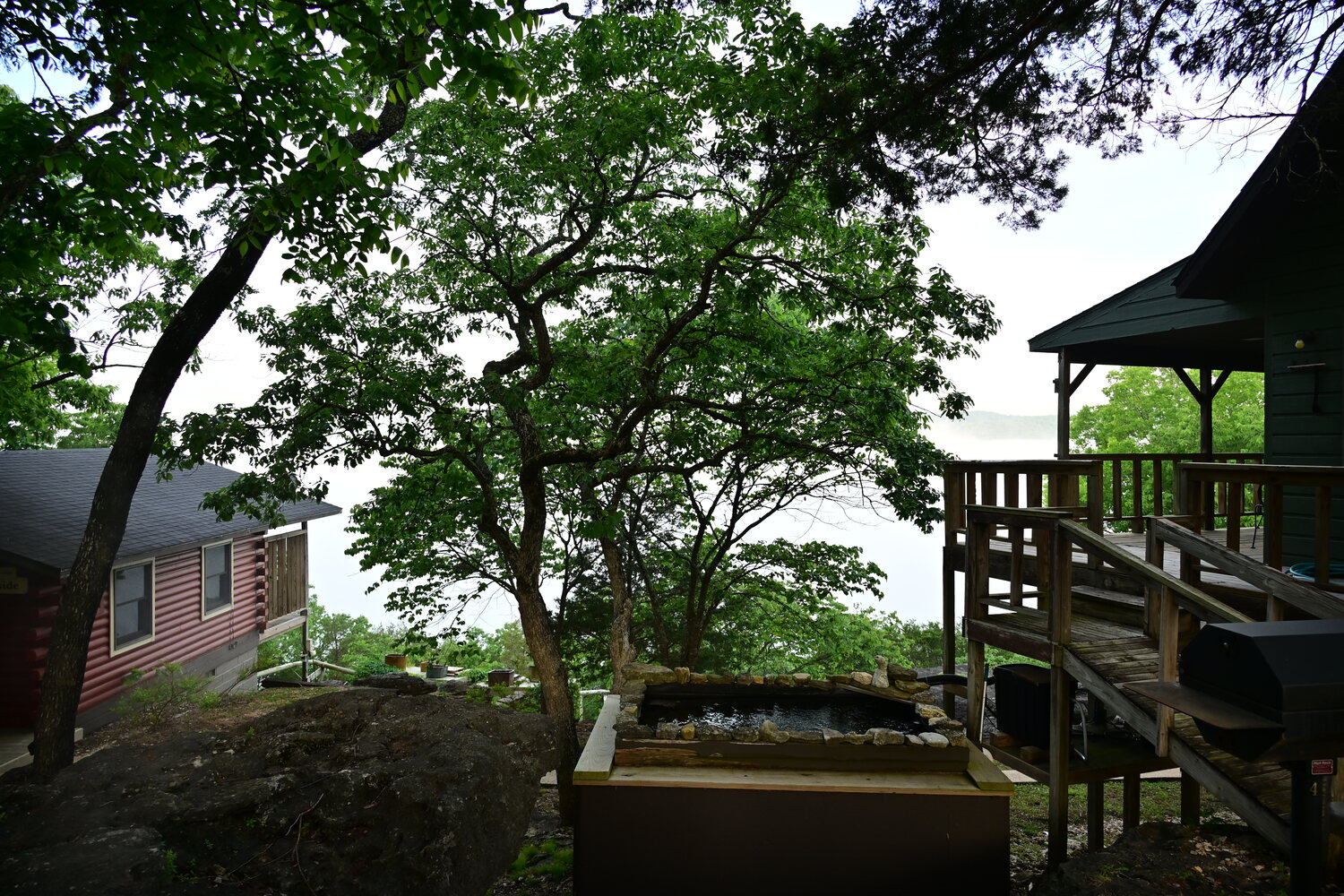 Private cabin deck shaded by trees with a view into the Ozark woods