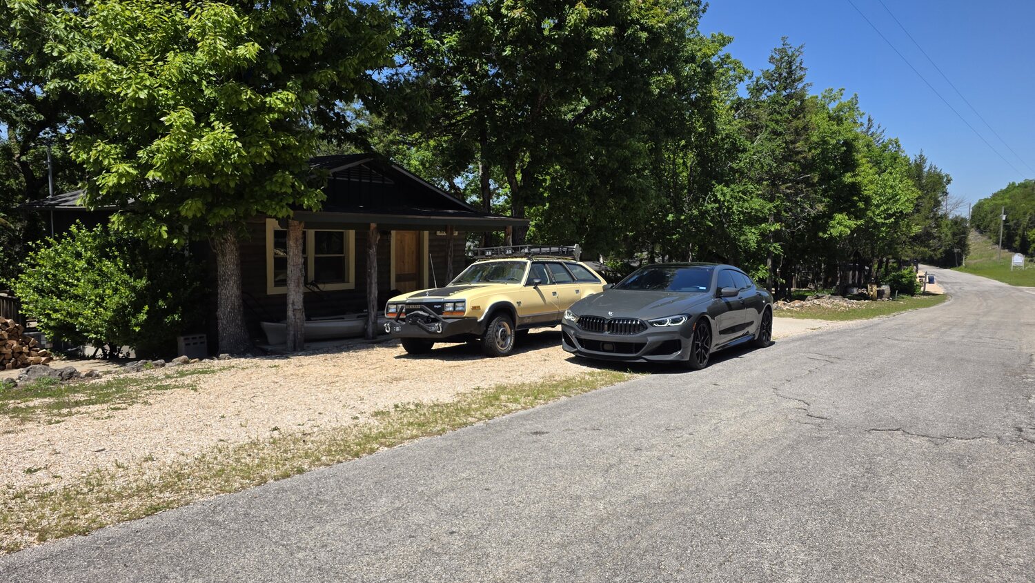 Log cabin and gravel drive among the trees on a sunny afternoon