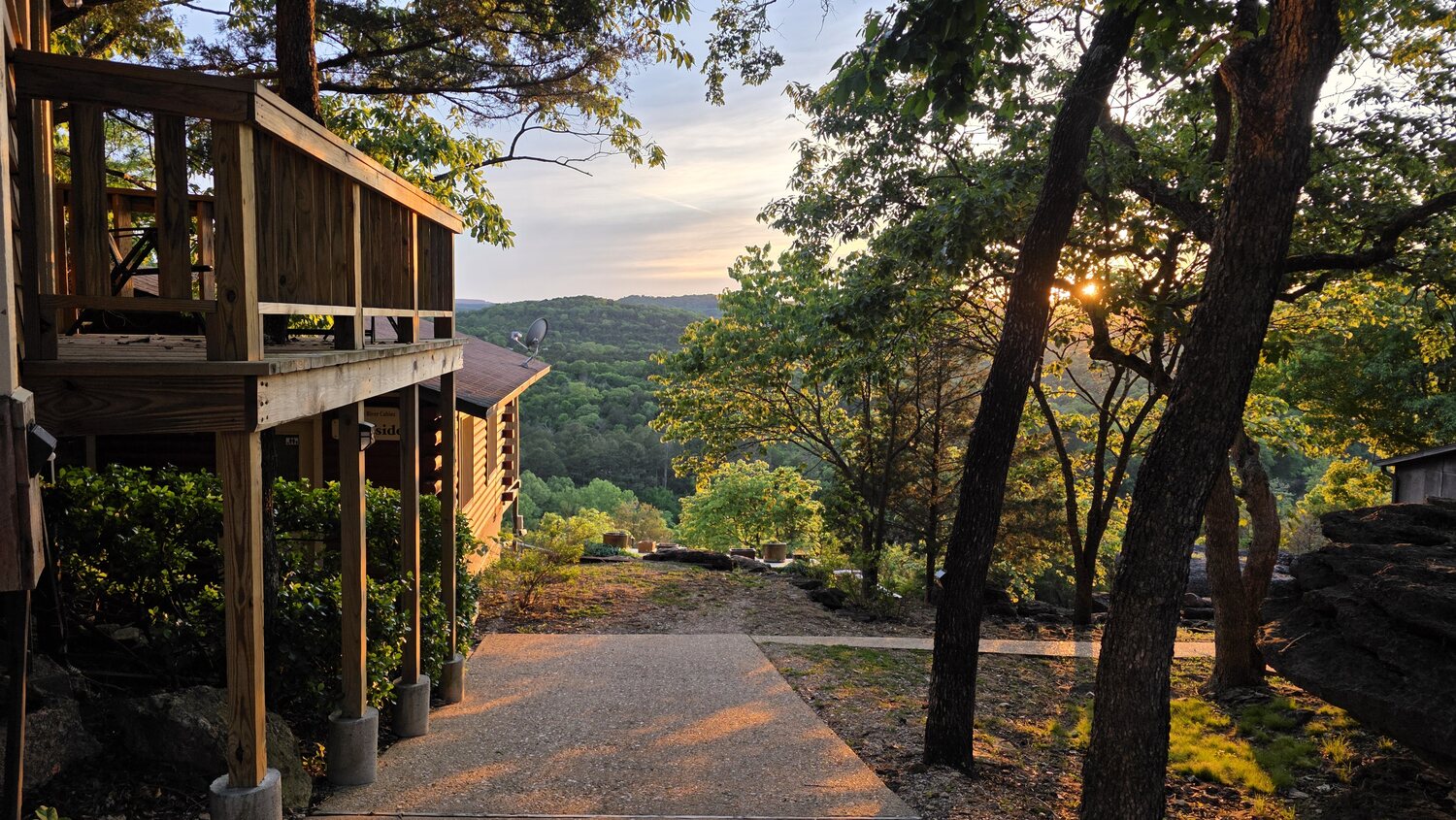 Log cabin and deck glowing in golden-hour light above the valley