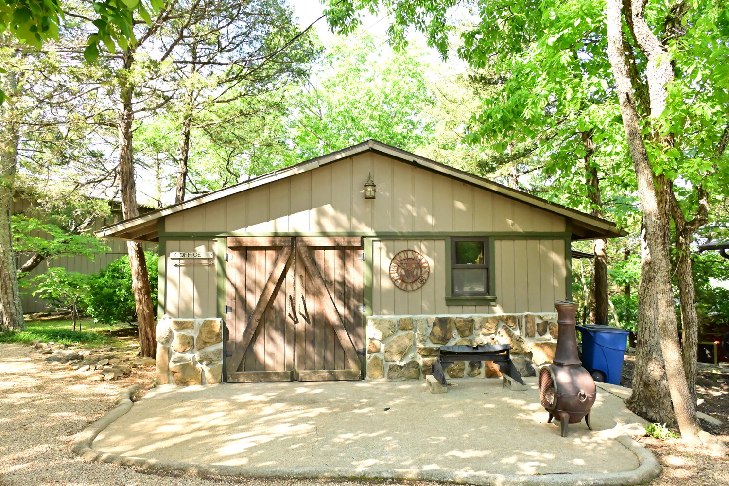 Quiet outdoor sitting area shaded by tall trees on the property